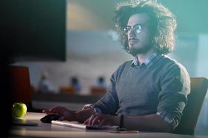 hombre trabajando en una computadora en una oficina oscura foto