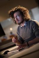 man working on computer in dark office photo