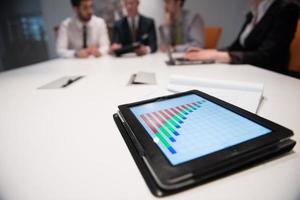 close up of touchpad with analytics documents at business meeting photo