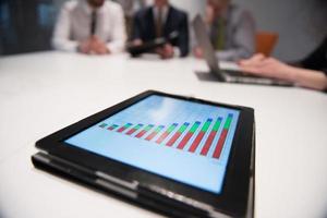 close up of touchpad with analytics documents at business meeting photo