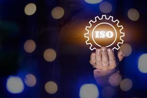 un hombre de negocios que tiene el icono del certificado iso, la luz de bokeh del paso de procesamiento iso, el control de documentos de calidad estándar para los productos de gestión de la organización y la industria, el espacio de copia para el diseño o el texto foto