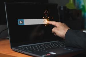 A businessman finger touch video footage bar on the laptop screen for searching information concept, computer graphic light with copy space for text photo