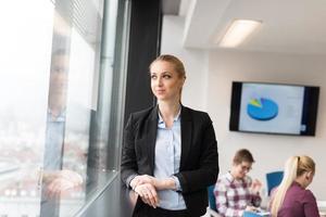 portrait of young business woman at office with team on meeting in background photo