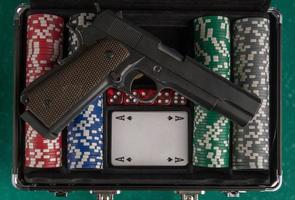 una toma superior de un arma en una caja de póquer abierta en un tablero verde.