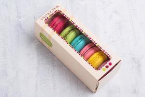 An angle shot of colorful French macarons placed in a cute box with a transparent top. photo