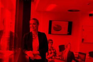 portrait of young business woman at office with team on meeting in background photo