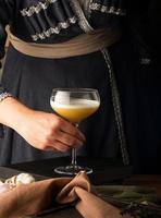 A vertical shot of a waitress presenting a cocktail photo