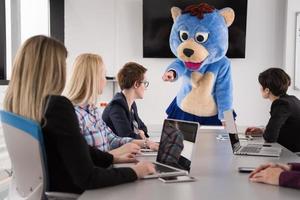 boss dresed as bear having fun with business people in trendy office photo