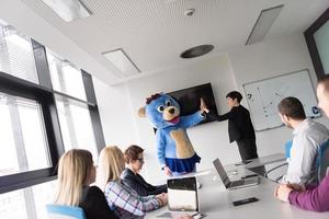 boss dresed as bear having fun with business people in trendy office photo