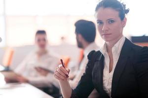 retrato de mujer mientras sostiene un bolígrafo en una reunión de negocios foto