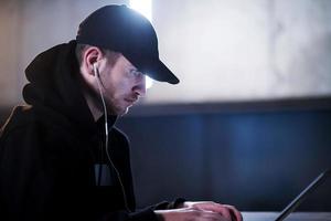 talented hacker using laptop computer while working in dark office photo