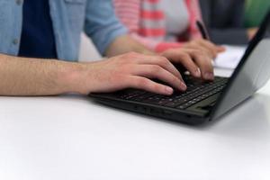 primer plano de las manos de los estudiantes escribiendo en la computadora portátil foto