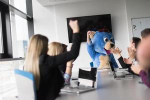 boss dresed as bear having fun with business people in trendy office photo