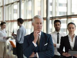 portrait of senior businessman as leader  with staff in background photo