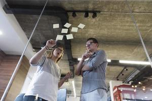 young couple at modern office interior writing notes on stickers photo