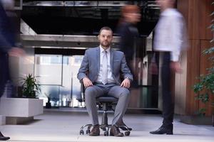 business man sitting in office chair, people group  passing by photo