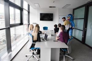 boss dresed as bear having fun with business people in trendy office photo