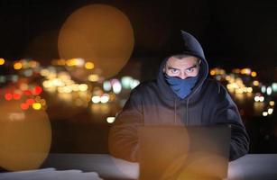 hacker using laptop computer while working in dark office photo