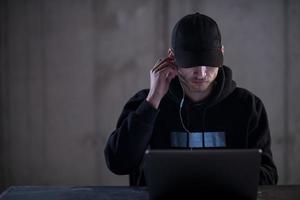 talented hacker using laptop computer while working in dark office photo
