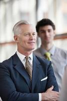 portrait of senior businessman as leader  with staff in background photo