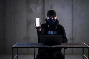 criminal hacker using laptop computer while working in dark office