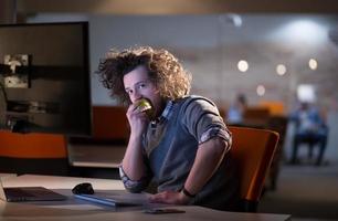 hombre comiendo manzana en su oficina foto