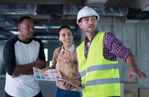 architect showing house design plans to a young multiethnic couple photo