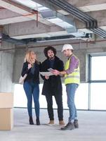 architect showing house design plans to a young couple photo