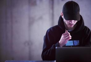 talented hacker using laptop computer while working in dark office photo