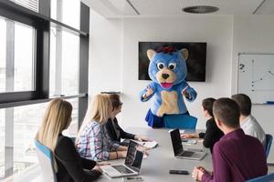 boss dresed as bear having fun with business people in trendy office photo