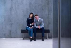 business couple using mobile phone while sitting on the bench photo