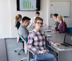 portrait of young business woman at office with team on meeting in background photo