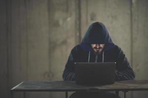 talented hacker using laptop computer while working in dark office photo