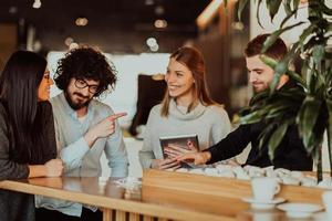 un grupo de personas en un descanso para tomar café usa computadoras portátiles, tabletas y teléfonos inteligentes mientras discuten nuevos proyectos comerciales. concepto de negocio. foto