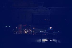 hacker using laptop computer while working in dark office photo