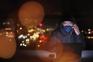 hacker using laptop computer while working in dark office photo