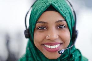 mujer musulmana africana con auriculares de teléfono ayudando y apoyando en línea foto