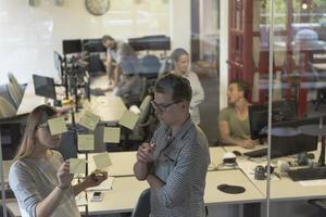 pareja joven en el interior de la oficina moderna escribiendo notas en pegatinas foto