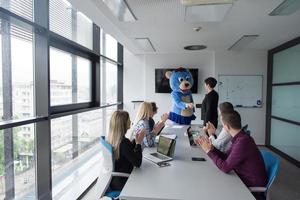 boss dresed as bear having fun with business people in trendy office photo