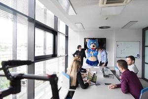 boss dresed as bear having fun with business people in trendy office photo