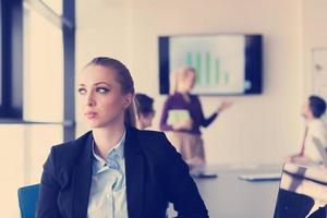 portrait of young business woman at office with team on meeting in background photo