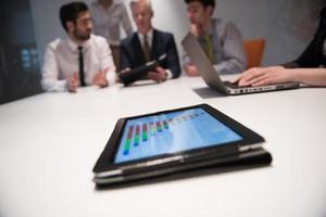 close up of touchpad with analytics documents at business meeting photo