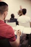 male student taking notes in classroom photo