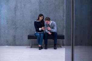 pareja de negocios usando teléfono móvil mientras está sentado en el banco foto