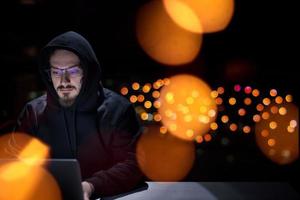 hacker using laptop computer while working in dark office photo