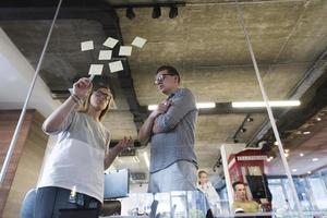 young couple at modern office interior writing notes on stickers photo