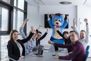 boss dresed as bear having fun with business people in trendy office photo