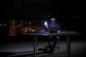 hacker using laptop computer while working in dark office photo