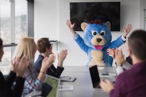 boss dresed as bear having fun with business people in trendy office photo