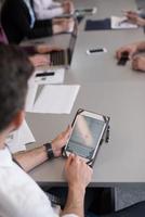 Cerca de las manos de un hombre de negocios usando una tableta en una reunión foto